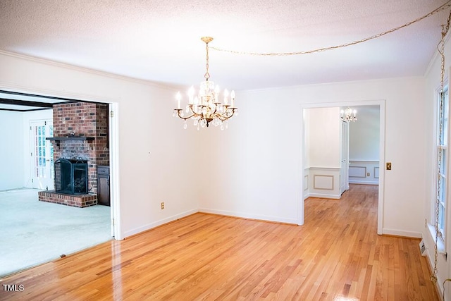 70 Sand Trap Ln, Roxboro, NC 27574 - unfurnished dining area featuring a chandelier, light wood-style floors, ornamental molding, a fireplace, and a textured ceiling