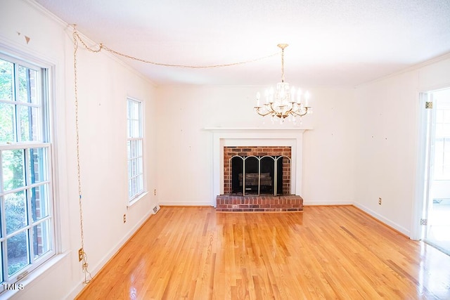 70 Sand Trap Ln, Roxboro, NC 27574 - unfurnished living room with light wood-style flooring, crown molding, a chandelier, and a fireplace