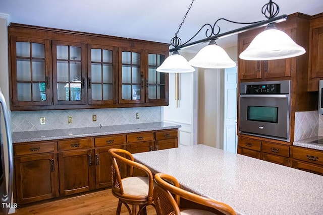 70 Sand Trap Ln, Roxboro, NC 27574 - kitchen with stainless steel oven, backsplash, glass insert cabinets, light wood-type flooring, and pendant lighting