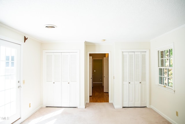 70 Sand Trap Ln, Roxboro, NC 27574 - unfurnished bedroom featuring two closets, light carpet, and crown molding
