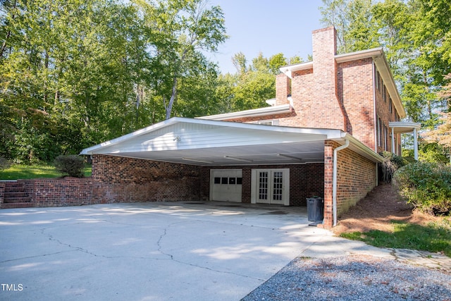 70 Sand Trap Ln, Roxboro, NC 27574 - view of side of home featuring an attached carport, concrete driveway, a chimney, brick siding, and french doors