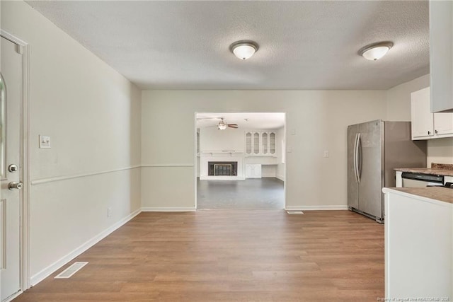 2619 Dumfries Dr, Fayetteville, NC 28306 - kitchen featuring light wood-style flooring, ceiling fan, a textured ceiling, white cabinetry, and freestanding refrigerator