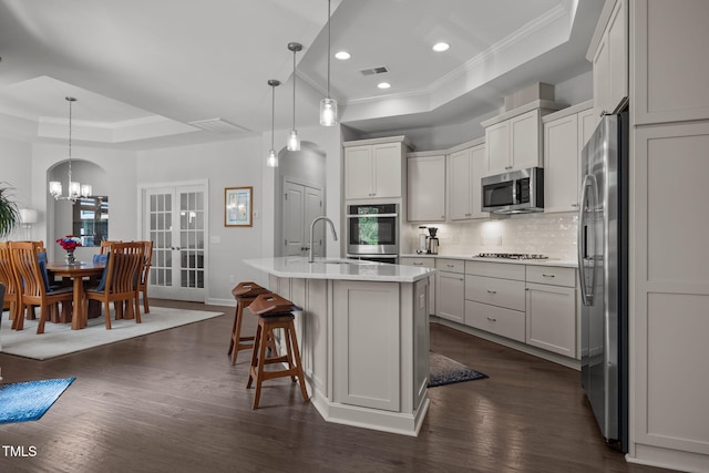 1372 Prevenient Dr, Wake Forest, NC 27587 - kitchen with a raised ceiling, appliances with stainless steel finishes, ornamental molding, tasteful backsplash, and dark wood-style flooring