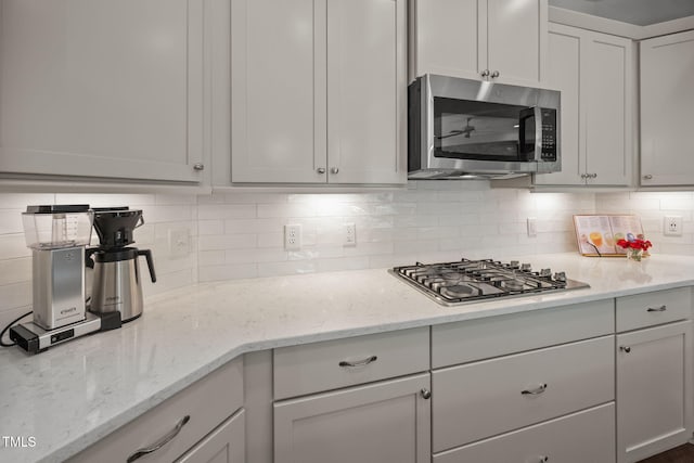 1372 Prevenient Dr, Wake Forest, NC 27587 - kitchen featuring stainless steel appliances, decorative backsplash, light stone countertops, and white cabinetry