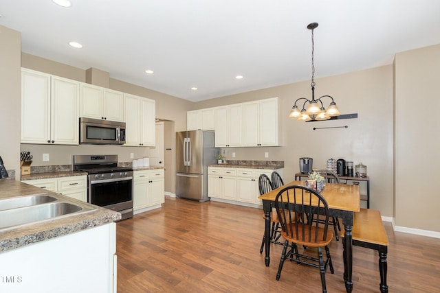 118 Truss Way, Durham, NC 27704 - kitchen featuring appliances with stainless steel finishes, a chandelier, wood finished floors, pendant lighting, and recessed lighting