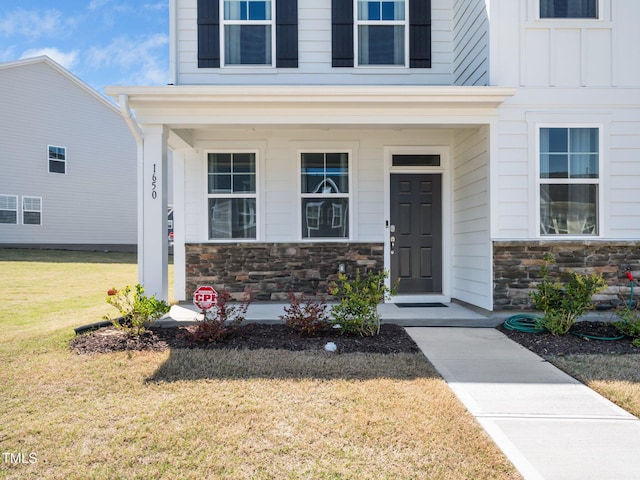 1650 Singing Bird Trl, Wake Forest, NC 27587 - doorway to property with stone siding, a porch, a yard, and board and batten siding