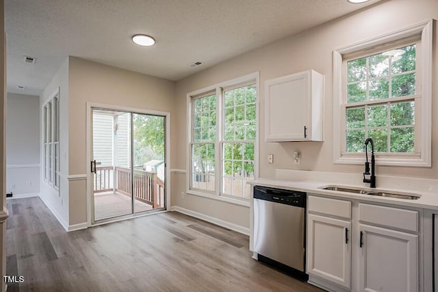 413 Hanska Way, Raleigh, NC 27610 - kitchen featuring stainless steel dishwasher, white cabinets, light wood-type flooring, light countertops, and plenty of natural light