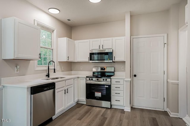 413 Hanska Way, Raleigh, NC 27610 - kitchen featuring stainless steel appliances, wood finished floors, white cabinets, and light countertops