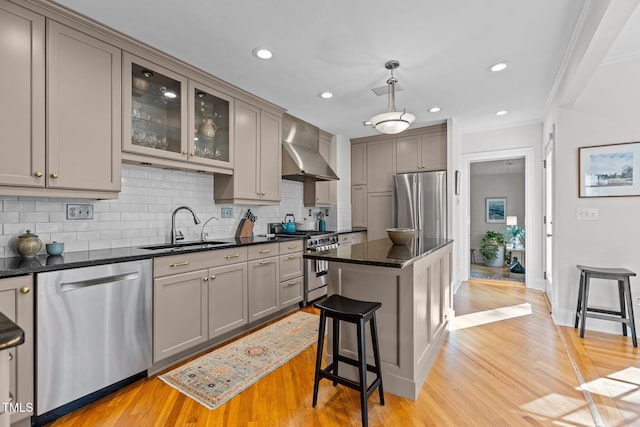 2706 Stuart Dr, Durham, NC 27707 - kitchen featuring wall chimney range hood, appliances with stainless steel finishes, gray cabinets, decorative backsplash, and light wood-style floors