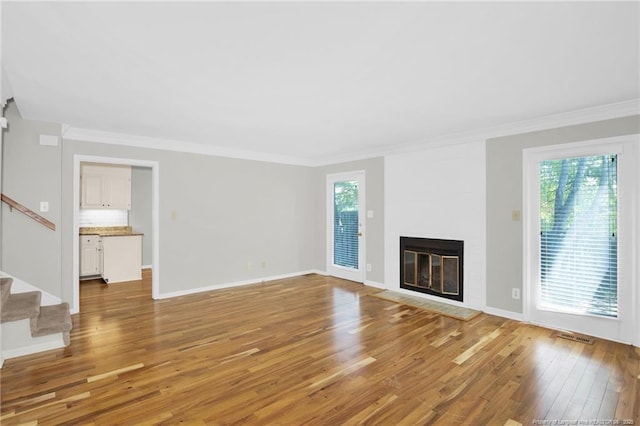 106 Woodrow St, Fayetteville, NC 28303 - unfurnished living room featuring light wood-style flooring, ornamental molding, stairway, and a fireplace with flush hearth