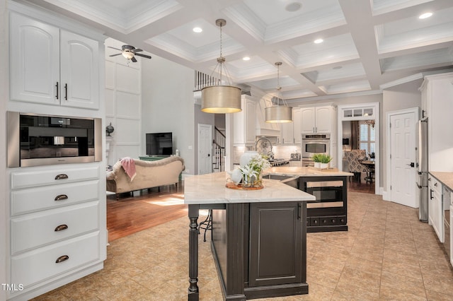12452 Richmond Run Dr, Raleigh, NC 27614 - kitchen with appliances with stainless steel finishes, white cabinets, an island with sink, coffered ceiling, and beam ceiling