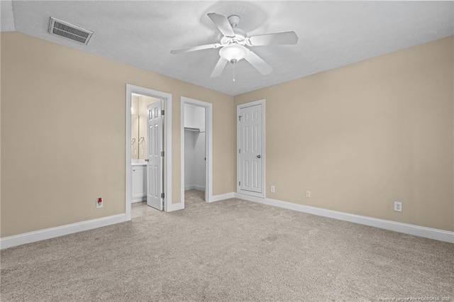 85 Shining Water Ln, Spring Lake, NC 28390 - unfurnished bedroom with light colored carpet, connected bathroom, a closet, a ceiling fan, and a walk in closet