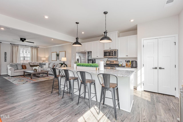 235 Misty Pike Dr, Raleigh, NC 27603 - kitchen with stainless steel appliances, light wood-style floors, a breakfast bar, white cabinetry, and open floor plan