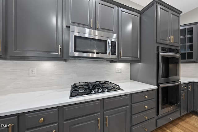 7112 Hasentree Way, Wake Forest, NC 27587 - kitchen with stainless steel appliances, decorative backsplash, gray cabinetry, wood finished floors, and glass insert cabinets
