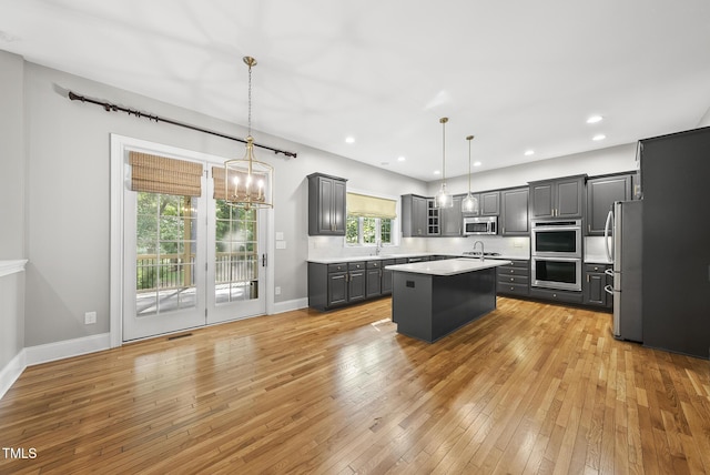 7112 Hasentree Way, Wake Forest, NC 27587 - kitchen featuring appliances with stainless steel finishes, gray cabinets, light countertops, an island with sink, and a chandelier