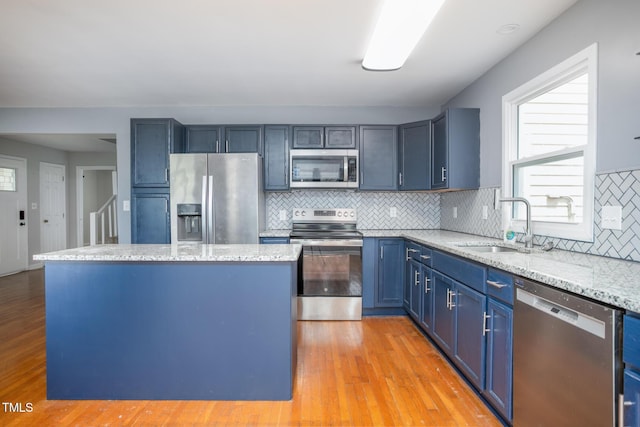 3542 Anderson Valley Rd, Mcleansville, NC 27301 - kitchen featuring appliances with stainless steel finishes, blue cabinetry, backsplash, a center island, and light wood-style flooring
