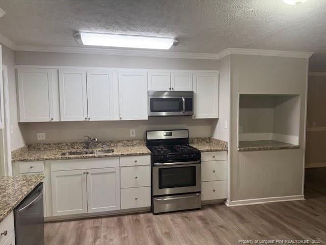 5027 Chesapeake Rd, Fayetteville, NC 28311 - kitchen with stainless steel appliances, light wood-type flooring, a textured ceiling, white cabinetry, and crown molding