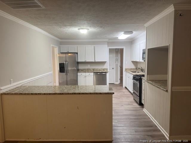 5027 Chesapeake Rd, Fayetteville, NC 28311 - kitchen featuring stainless steel appliances, light stone counters, a peninsula, a textured ceiling, and ornamental molding