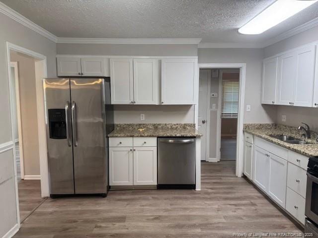 5027 Chesapeake Rd, Fayetteville, NC 28311 - kitchen with stainless steel appliances, ornamental molding, white cabinets, a textured ceiling, and light wood finished floors