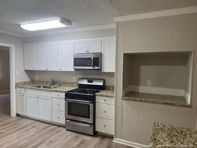 5027 Chesapeake Rd, Fayetteville, NC 28311 - kitchen featuring appliances with stainless steel finishes, light wood finished floors, a textured ceiling, white cabinets, and crown molding