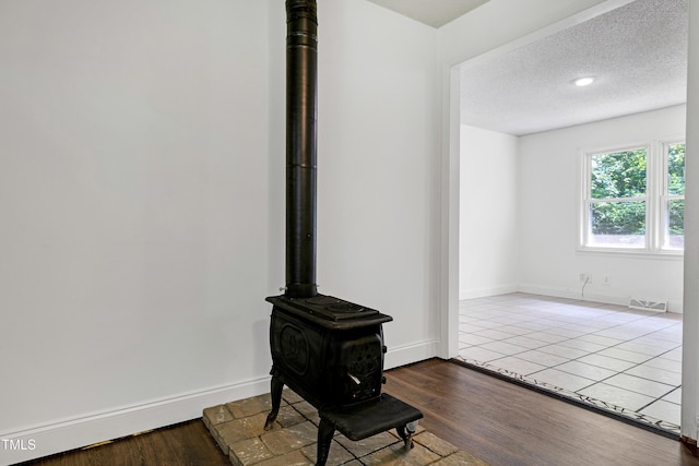 8905 Dukes Lake Rd, Zebulon, NC 27597 - detailed view of a wood stove, wood finished floors, and a textured ceiling
