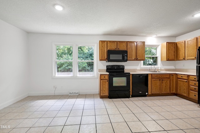 8905 Dukes Lake Rd, Zebulon, NC 27597 - kitchen featuring black appliances, a textured ceiling, brown cabinets, light countertops, and light tile patterned floors