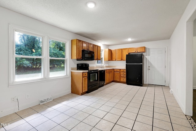 8905 Dukes Lake Rd, Zebulon, NC 27597 - kitchen with black appliances, light countertops, a textured ceiling, brown cabinets, and light tile patterned floors