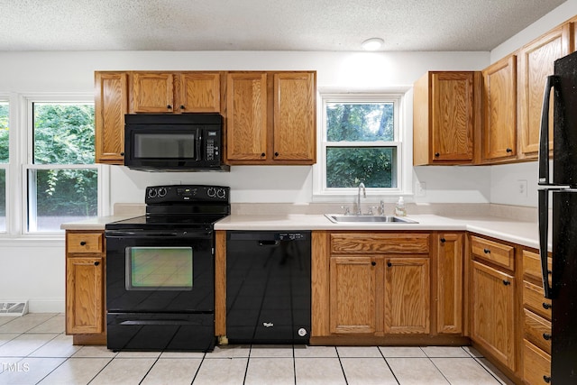 8905 Dukes Lake Rd, Zebulon, NC 27597 - kitchen featuring black appliances, plenty of natural light, a textured ceiling, and light tile patterned floors
