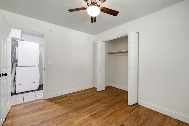 8905 Dukes Lake Rd, Zebulon, NC 27597 - unfurnished bedroom featuring stacked washer and clothes dryer, light wood-style flooring, a ceiling fan, and a closet