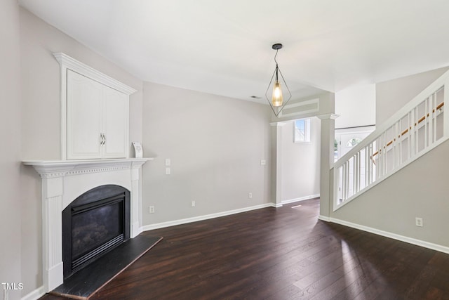 1212 Southgate Dr, Raleigh, NC 27610 - unfurnished living room featuring a glass covered fireplace, dark wood-style floors, stairway, and decorative columns