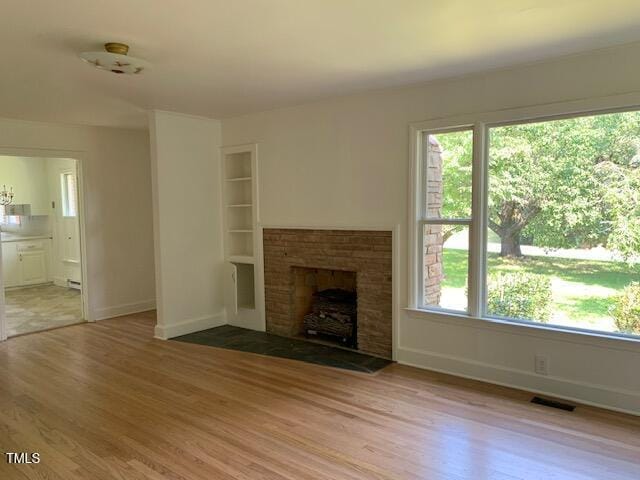 1003 Summerville Mamers Rd, Lillington, NC 27546 - unfurnished living room featuring light wood-type flooring, plenty of natural light, and a brick fireplace