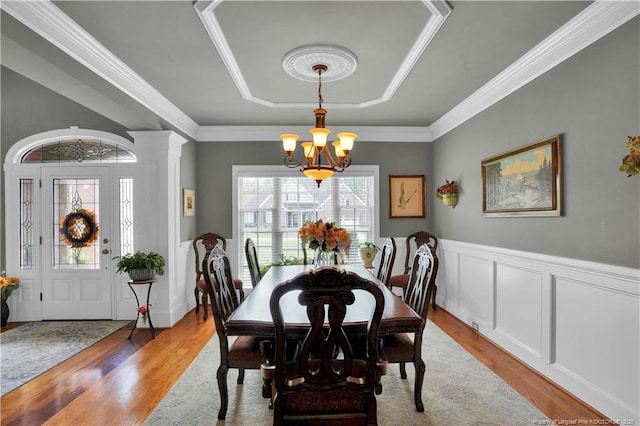 2825 Sand Trap Ln, Hope Mills, NC 28348 - dining room with a raised ceiling, a chandelier, light wood-style flooring, a wainscoted wall, and crown molding