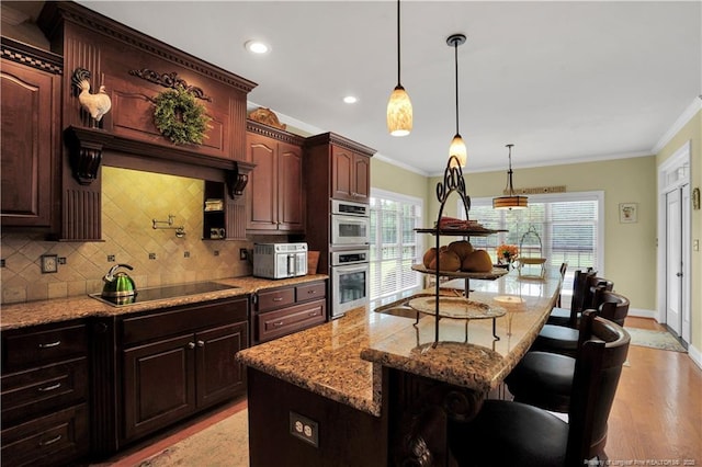 2825 Sand Trap Ln, Hope Mills, NC 28348 - kitchen with black electric stovetop, tasteful backsplash, a kitchen bar, ornamental molding, and stainless steel double oven