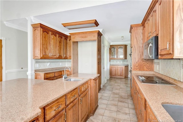 1190 Mckeller Rd, Fairmont, NC 28340 - kitchen featuring stainless steel microwave, black electric stovetop, ornamental molding, light stone countertops, and backsplash