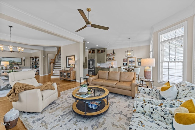 12510 Megan Hill Ct, Raleigh, NC 27614 - living area with stairway, a chandelier, a ceiling fan, wood finished floors, and crown molding