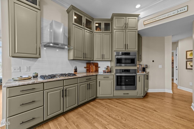 12510 Megan Hill Ct, Raleigh, NC 27614 - kitchen featuring wall chimney exhaust hood, appliances with stainless steel finishes, gray cabinets, decorative backsplash, and ornamental molding
