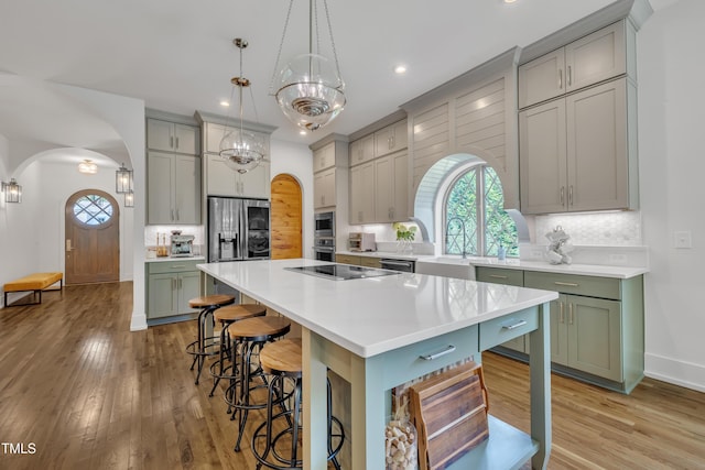 2203 Meadowcreek Dr, Durham, NC 27705 - kitchen with arched walkways, a kitchen breakfast bar, green cabinetry, light wood-type flooring, and recessed lighting