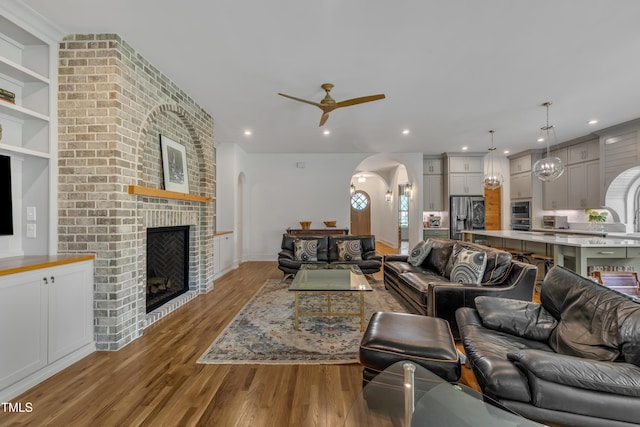 2203 Meadowcreek Dr, Durham, NC 27705 - living room featuring arched walkways, ceiling fan, wood finished floors, a fireplace, and recessed lighting