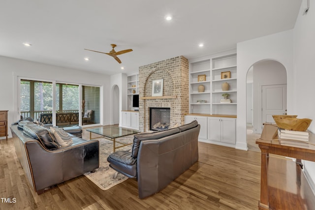 2203 Meadowcreek Dr, Durham, NC 27705 - living room featuring light wood-type flooring, ceiling fan, arched walkways, a brick fireplace, and recessed lighting