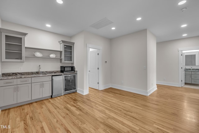 2203 Meadowcreek Dr, Durham, NC 27705 - kitchen featuring black microwave, gray cabinetry, open shelves, beverage cooler, and light wood finished floors