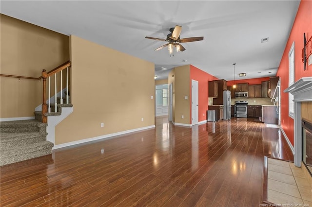 6204 Yorkie Ct, Stedman, NC 28391 - unfurnished living room featuring ceiling fan, dark wood-type flooring, stairs, and a fireplace with flush hearth