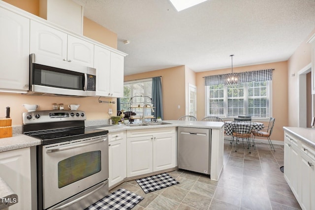 683 Castleberry Rd, Clayton, NC 27527 - kitchen with appliances with stainless steel finishes, a chandelier, a peninsula, healthy amount of natural light, and a textured ceiling