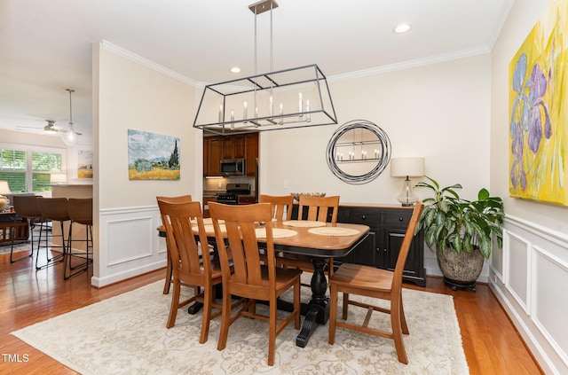 5030 Homeplace Dr, Apex, NC 27539 - dining area featuring ornamental molding, wood finished floors, a decorative wall, wainscoting, and a ceiling fan