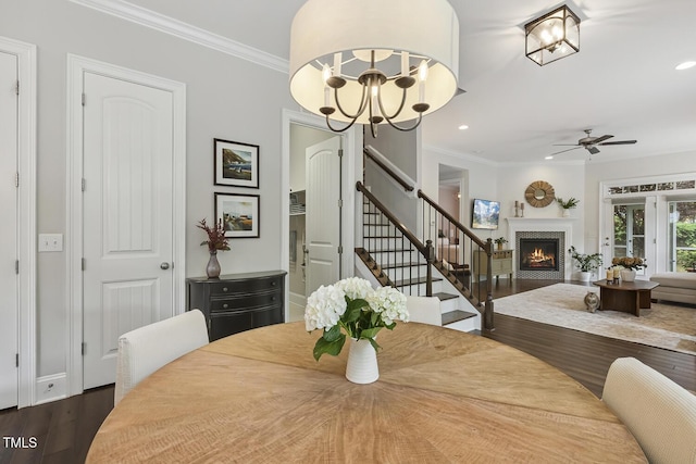 669 Fallon Grove Way, Raleigh, NC 27608 - dining space featuring a ceiling fan, a lit fireplace, dark wood-style flooring, ornamental molding, and stairway