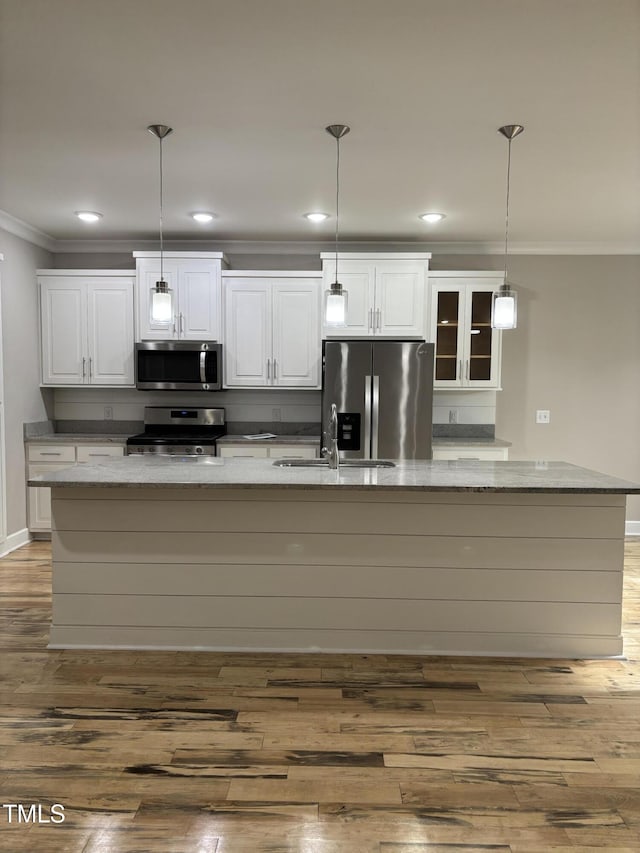 1119 Sagamore Dr, Louisburg, NC 27549 - kitchen featuring appliances with stainless steel finishes, ornamental molding, a spacious island, white cabinets, and wood finished floors