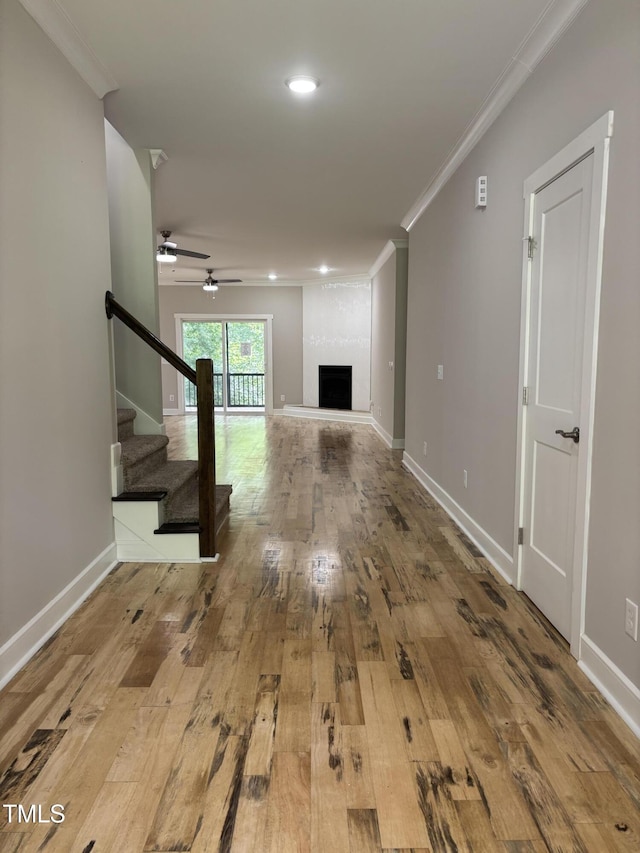 1119 Sagamore Dr, Louisburg, NC 27549 - unfurnished living room featuring wood-type flooring, crown molding, stairs, ceiling fan, and a large fireplace