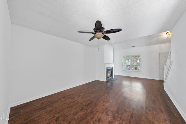 241 Commons Dr, Holly Springs, NC 27540 - unfurnished living room featuring dark wood finished floors, a fireplace with flush hearth, ceiling fan, and a textured ceiling