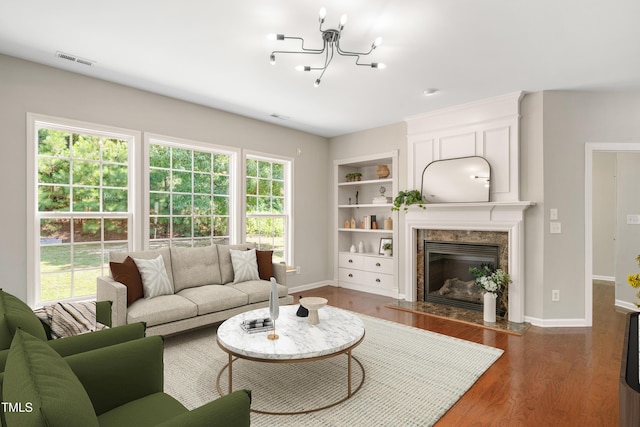 2021 Patapsco Dr, Apex, NC 27523 - living room featuring wood finished floors, a chandelier, built in shelves, and a high end fireplace
