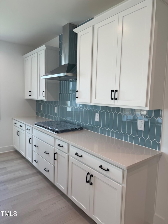 3731 Lebrun Path Unit 150Gunnison Cl, Fuquay Varina, NC 27526 - kitchen featuring wall chimney exhaust hood, stainless steel gas stovetop, light wood-type flooring, backsplash, and white cabinetry