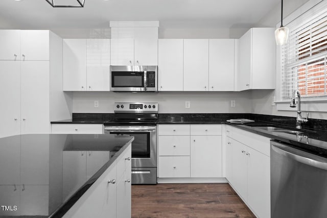 216 Whitfield St, Enfield, NC 27823 - kitchen featuring appliances with stainless steel finishes, dark wood-style flooring, white cabinetry, and decorative light fixtures
